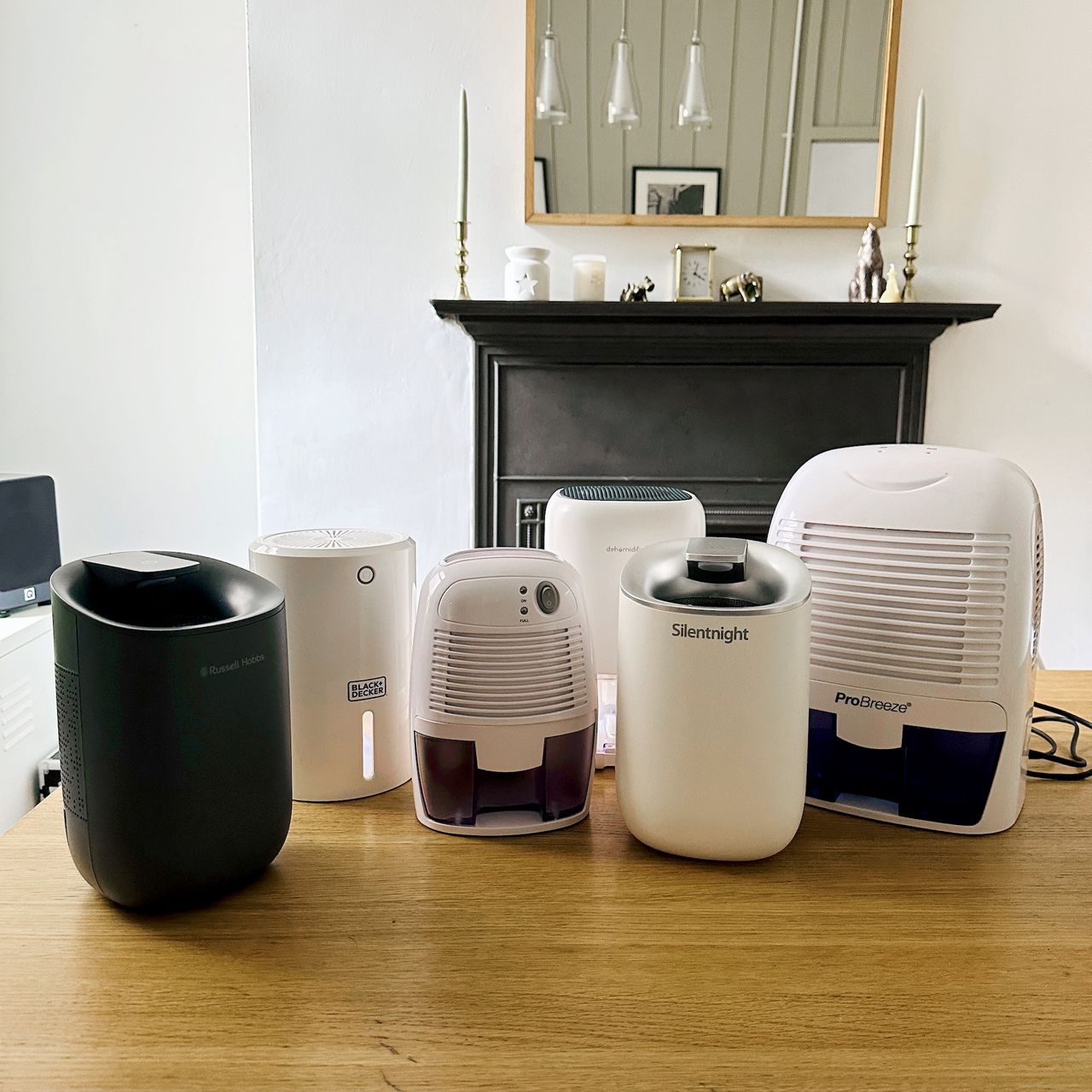 The best dehumidifiers under &pound;100 lined up on a wooden dining table ready for testing