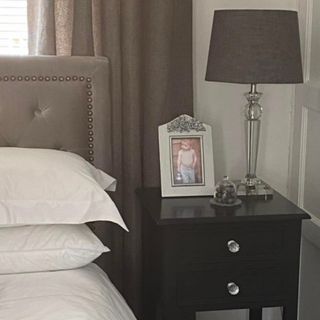black bedside table with a lamp and photo frame