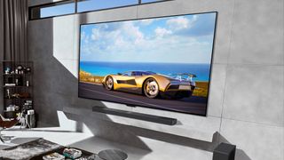 LG M4 OLED TV tegen een grijze wand met een auto op het scherm