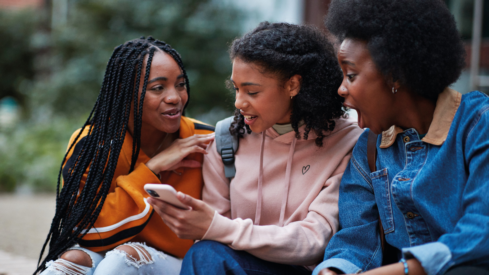 Young people in conversation, one of them holding a phone