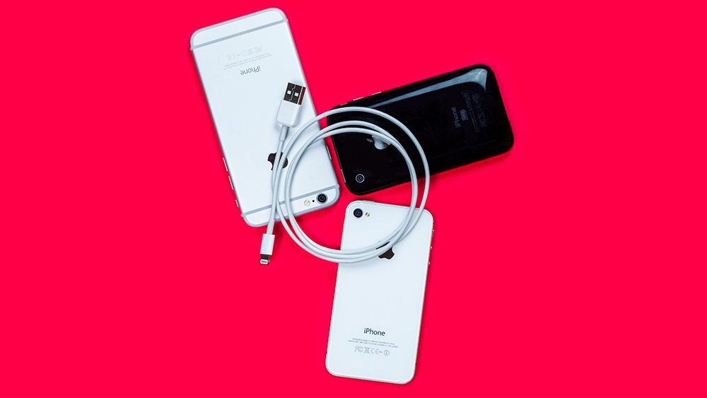 An Apple Lightning cable to USB cable and three iPhones on a red background 