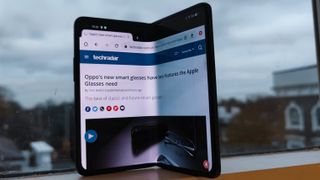 En Oppo Find N står upplutad mot ett fönster, med en TechRadar-artikel på skärmen.