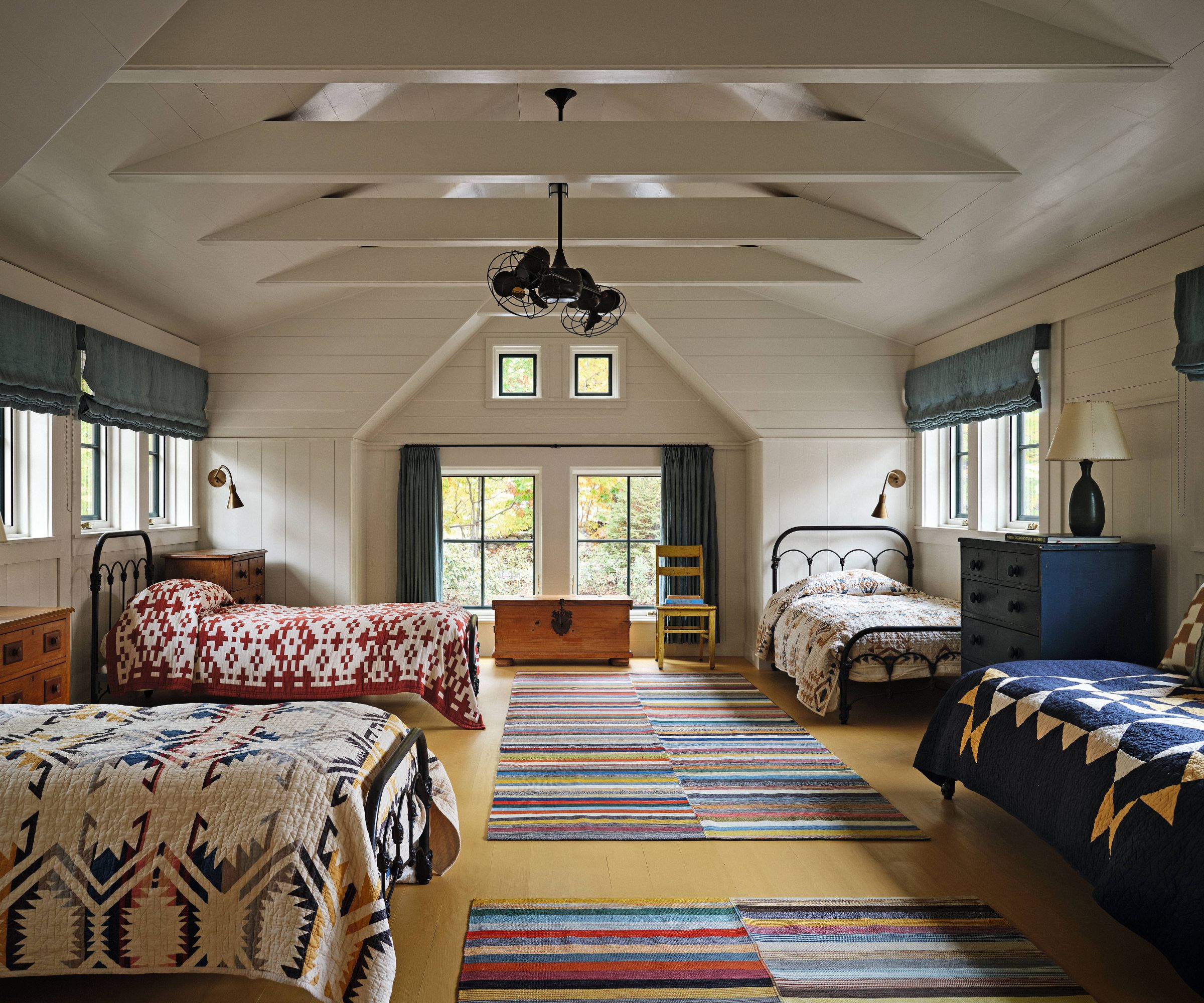 Bunk room in the roof with beams and 4 beds with patterned quilts