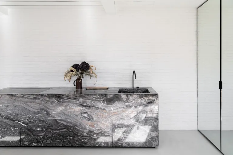 Grenelle flat by Studio Vincent Eschalier focussing on a marble kitchen against a wall.