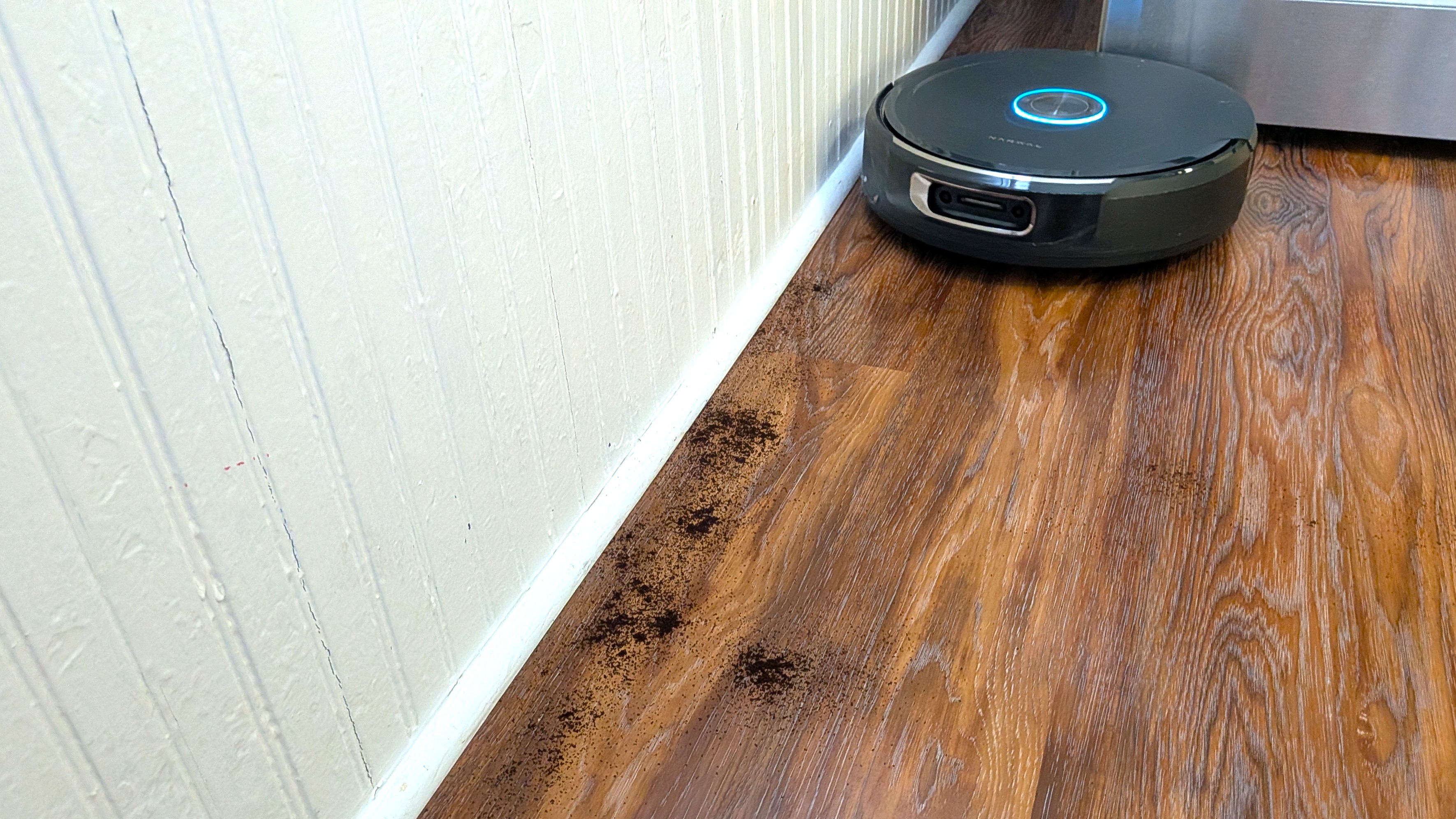 Narwal Flow 2 robot vacuum preparing to clean soil from edge of room beside baseboard