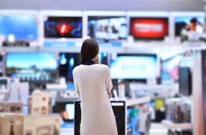 A woman looking at a wall of televisions