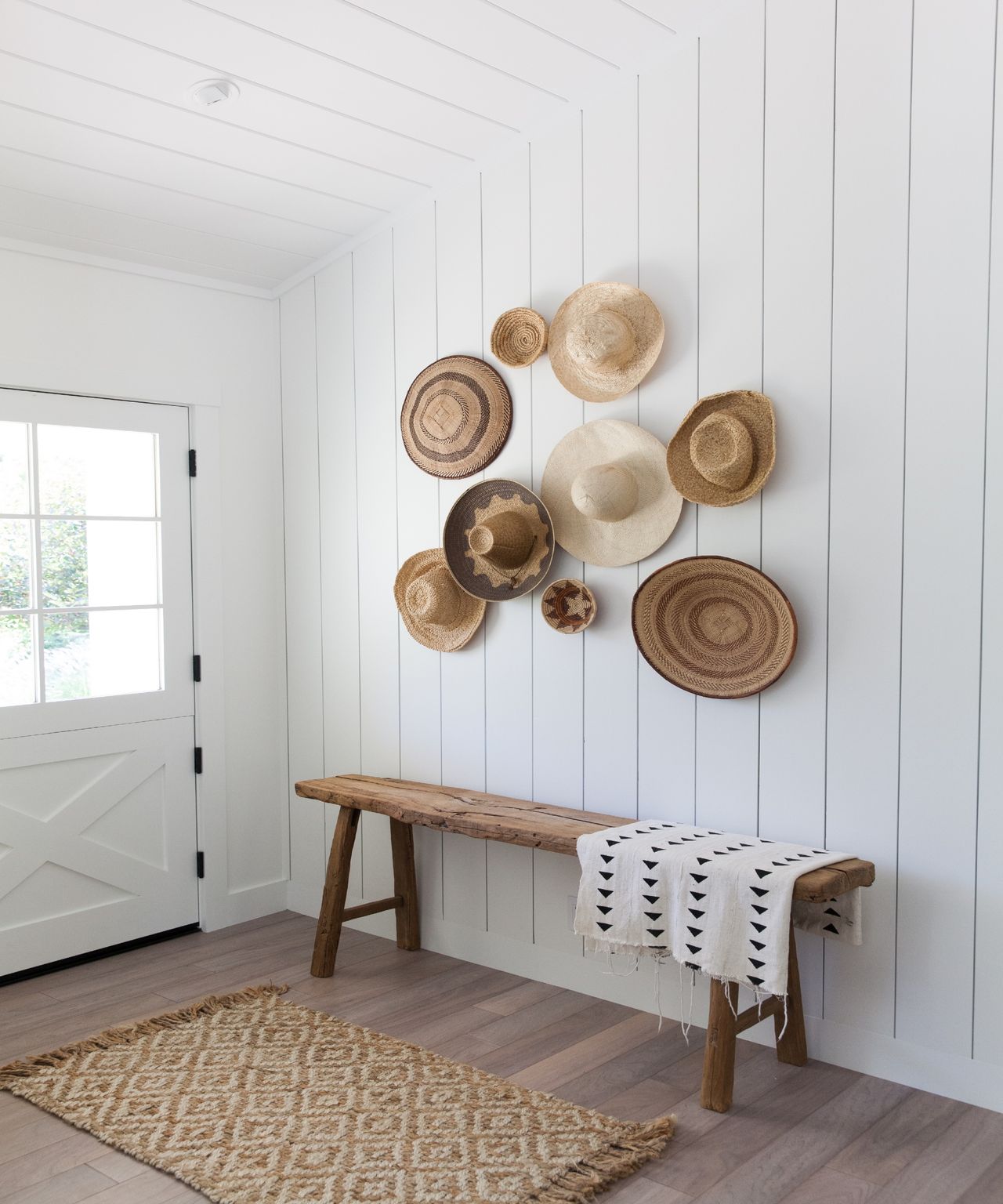 White paneled entryway with hats on the wall