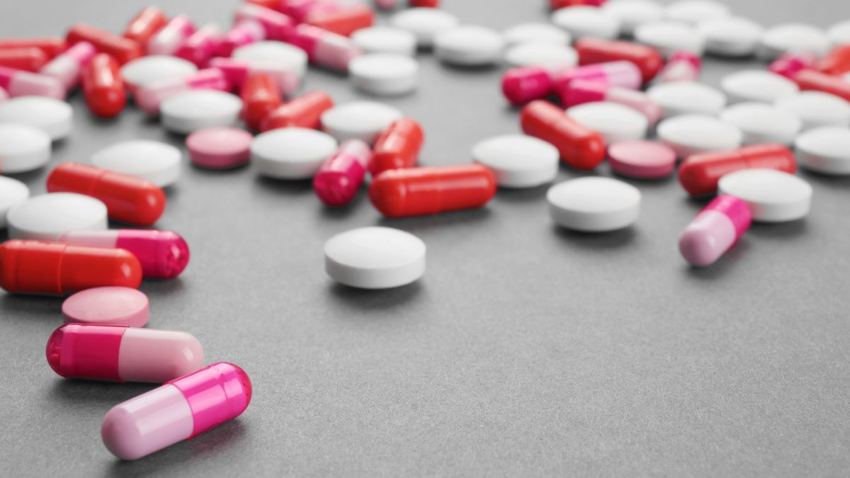 A handful of colourful pills scattered on a grey surface