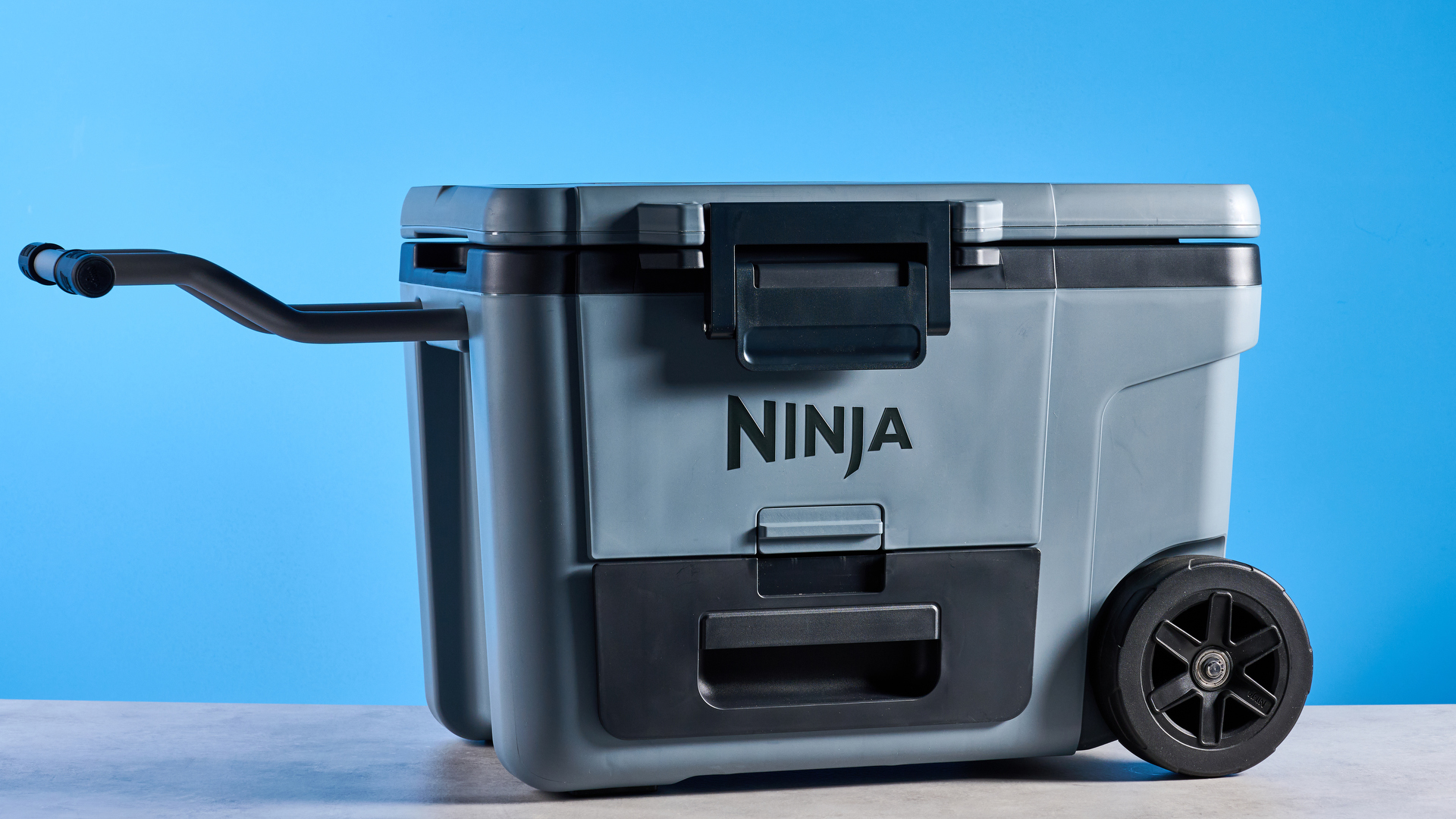 The Ninja FrostVault 45QT Wheeled Cooler photographed in front of a blue background.