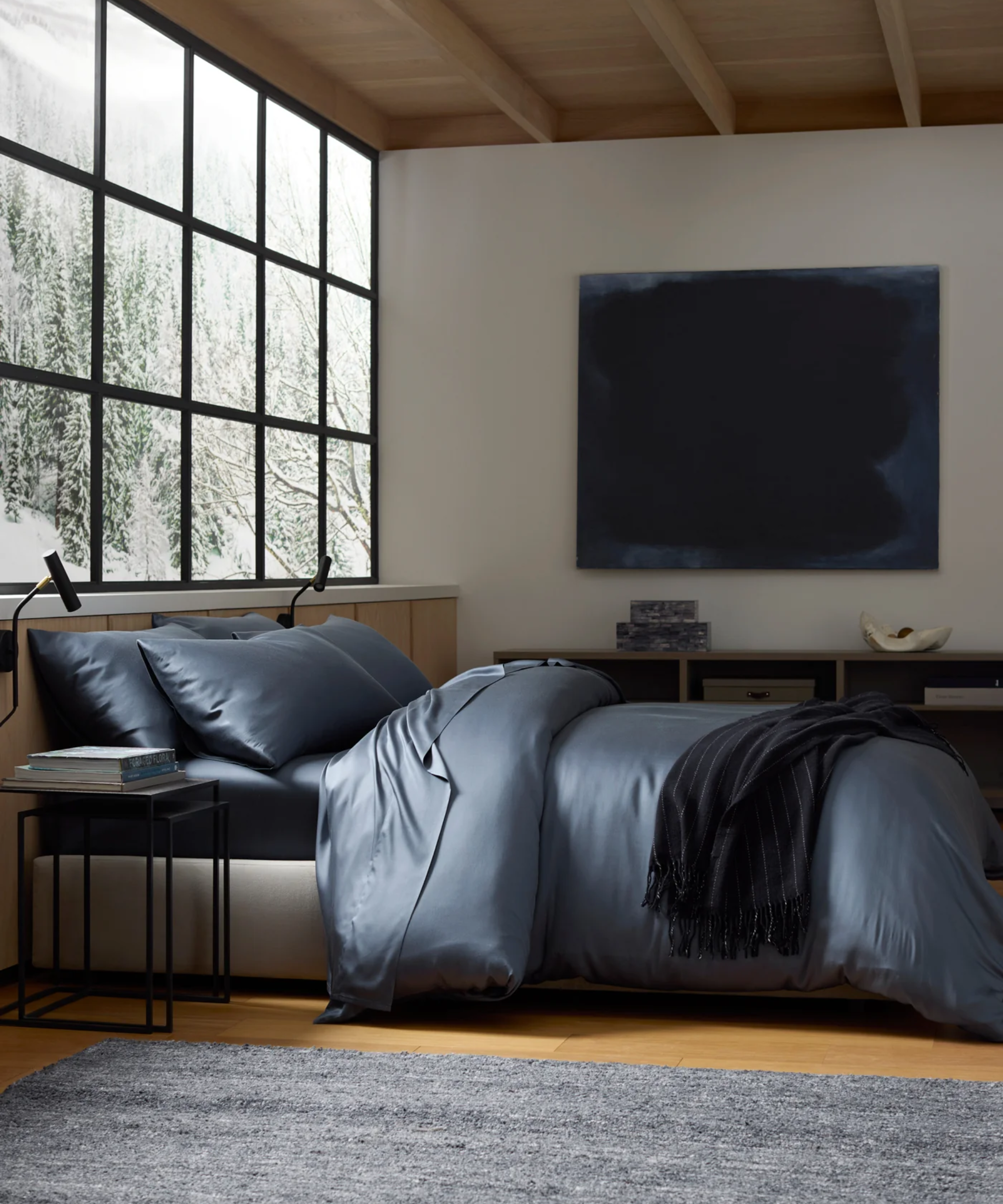 Minimalist, wintertime bedroom featuring a sleek-lined modern bed frame and cool blue viscose bedding