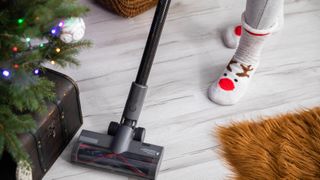 Someone vacuuming around a Christmas tree