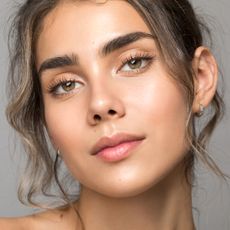 eyebrow tinting - image of woman looking into the camera with beautiful glowy skin and groomed brows