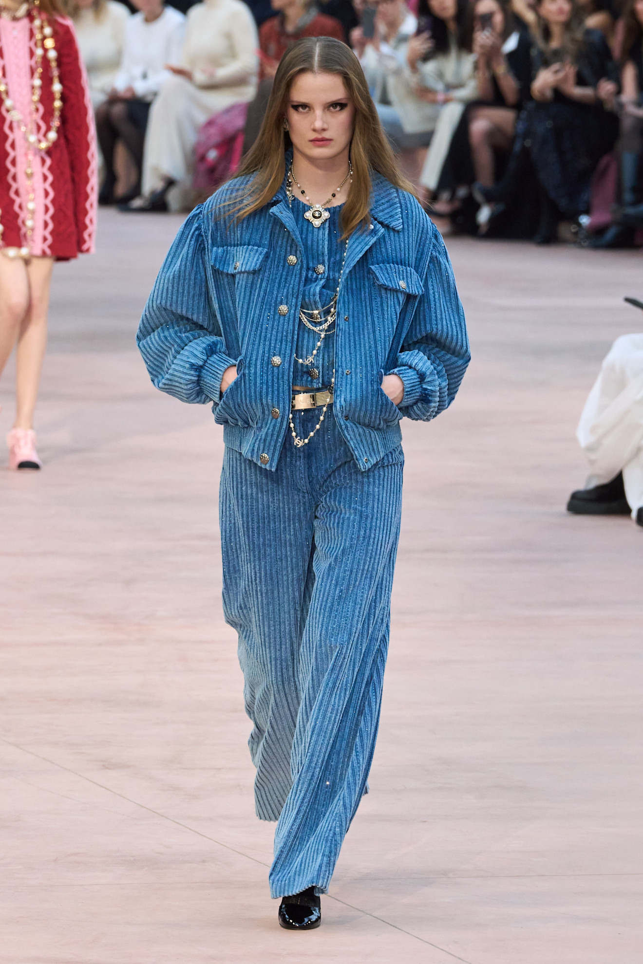 The Chanel Autumn Winter 2025 runway show. The model wears a full corduroy set, including mid blue trousers.