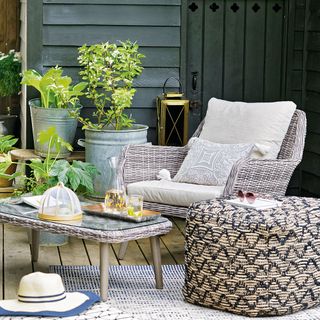 rattan outdoor furniture on rug surrounded by plants