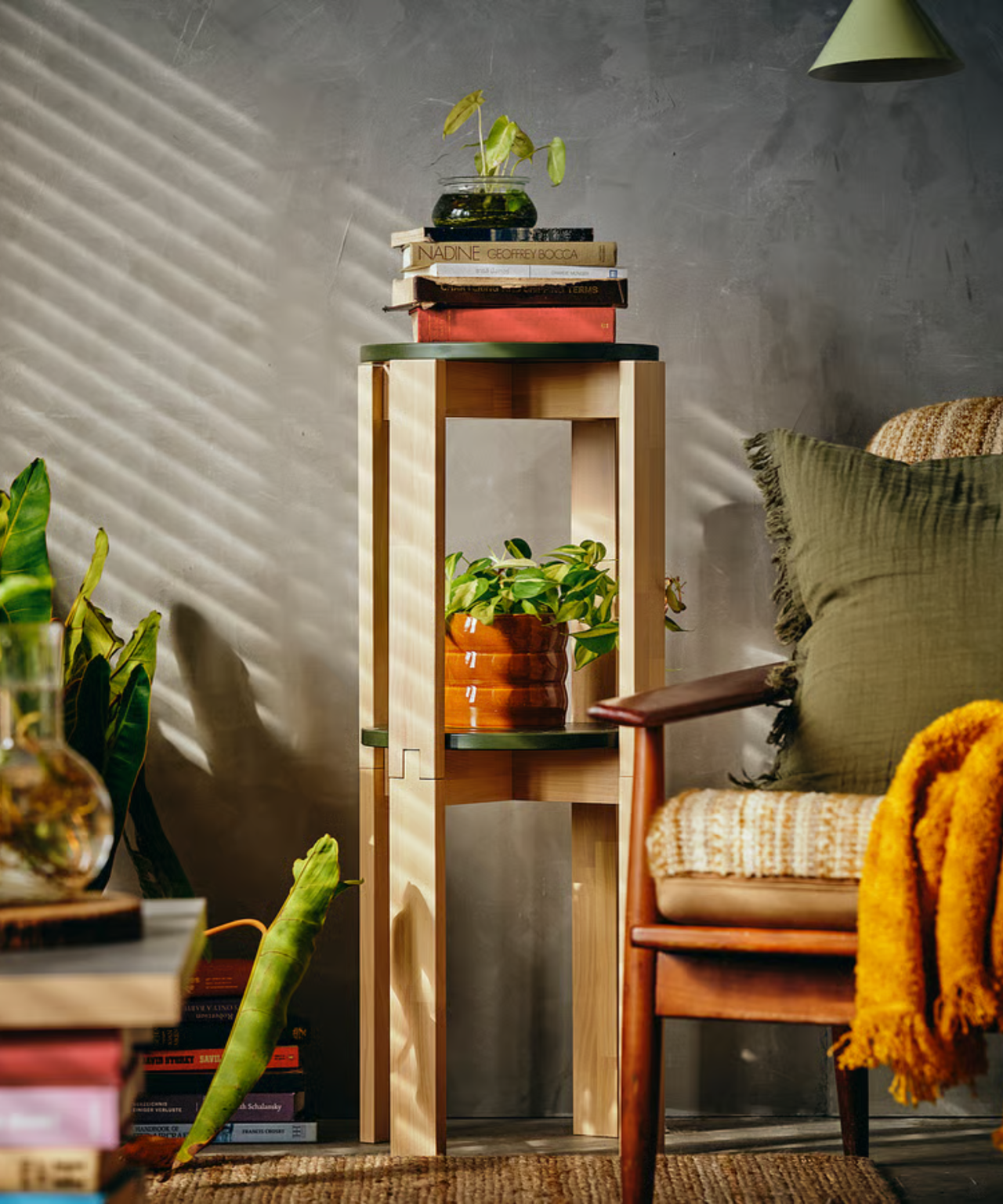 a stack of two wooden stools with plants and books on them in a room with an accent chair