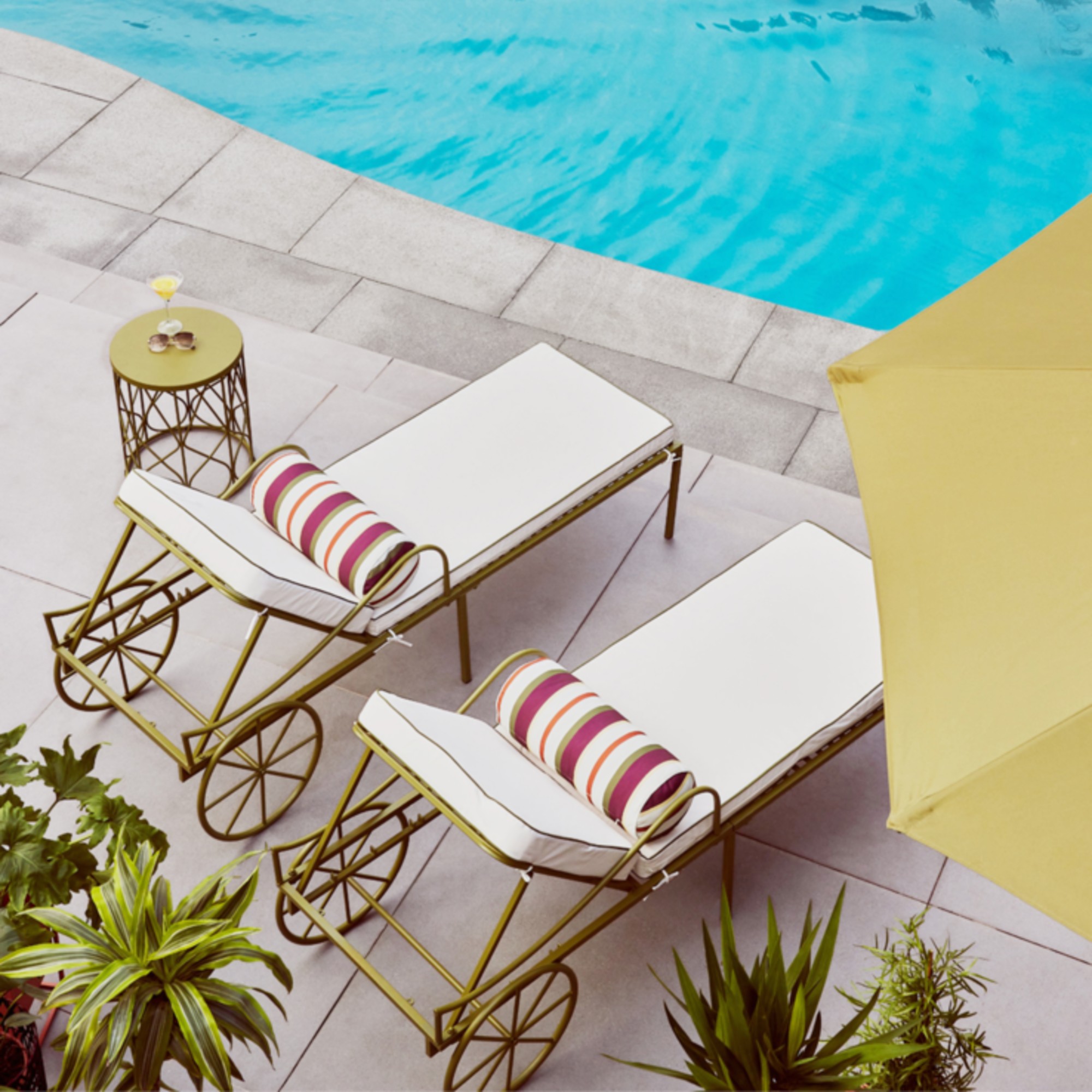 Two sunloungers from QVC's Studio 70 collection by the pool with a yellow parasol next to them