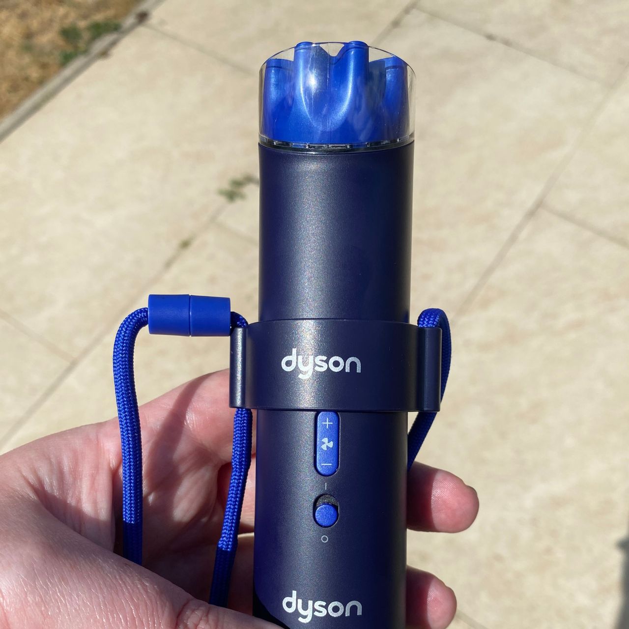 Dyson HushJet Mini Cool fan attached to the neck dock outside, with a patio in the background