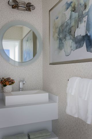 bathroom basin with round mirror and modern artwork