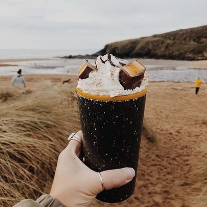 Circular Co Coffee Cup in hand with cream and chocolate chunks and sauce