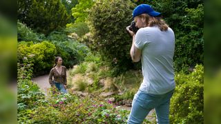 A man using a Nikon camera to photograph a portrait of a model using the Brenizer method