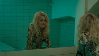 Lene (Mariann Hole) stares at herself in a bathroom mirror in Milf of Norway