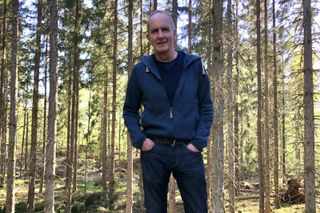 Kevin McCloud in a forest with his hands in his pocket