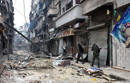 Government forces walk through a neighborhood in Aleppo.
