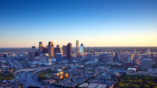 The Dallas skyline is a colorful landscape in late afternoon light. Interstates 45 and 35 converge in a orderly design.