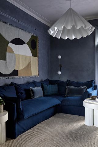 Living room with dark blue limewash walls, dark blue velvet sofa and light grey-blue limewash ceiling