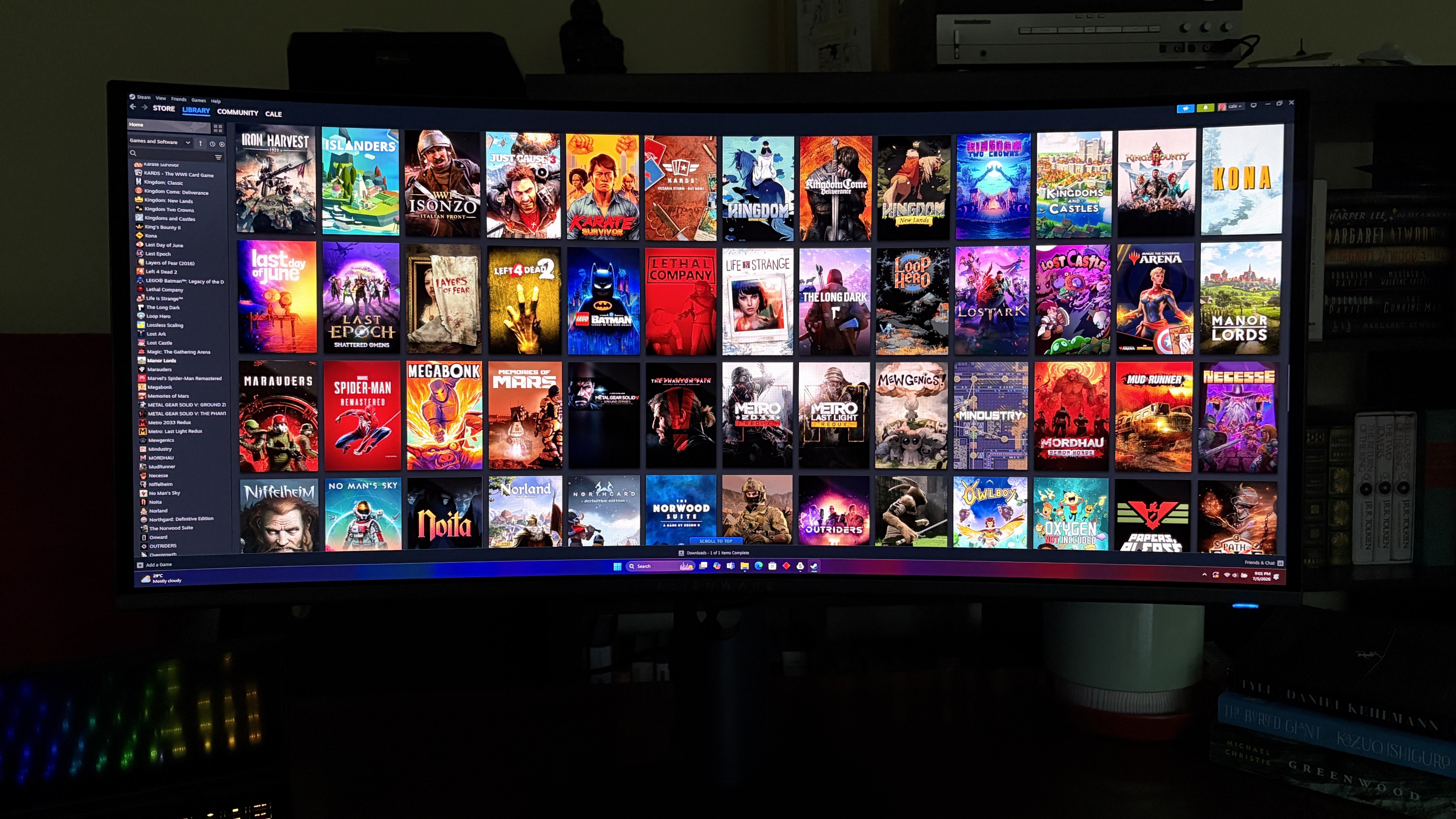 A curved Alienware AW3426DW computer monitor displaying a colorful digital library of various video game covers arranged in a grid format.