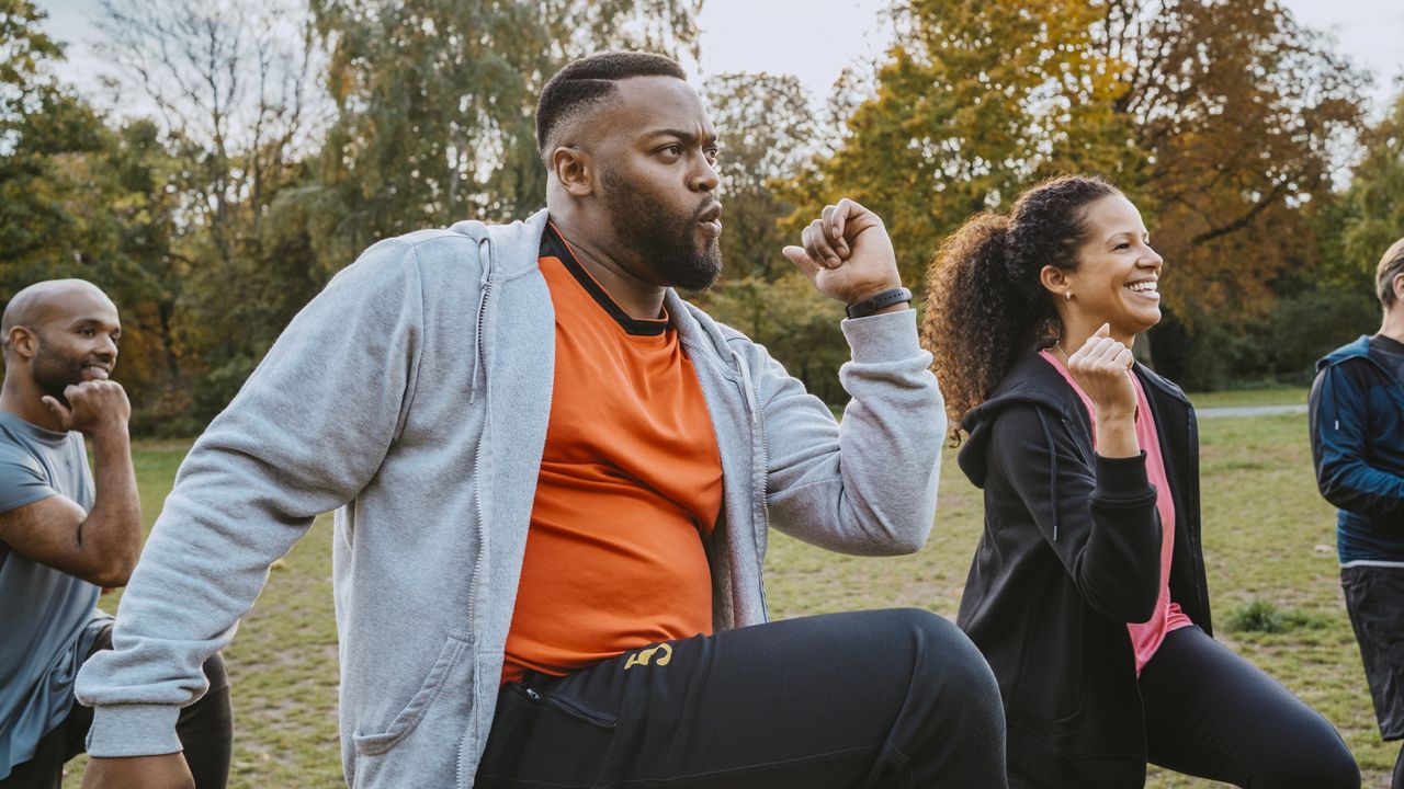 Young adults smile as they attend an outside exercise class.