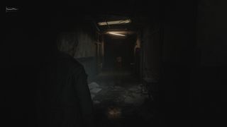 Looking down a spooky hallway in Silent Hill 2 remake with a monster at the end of it