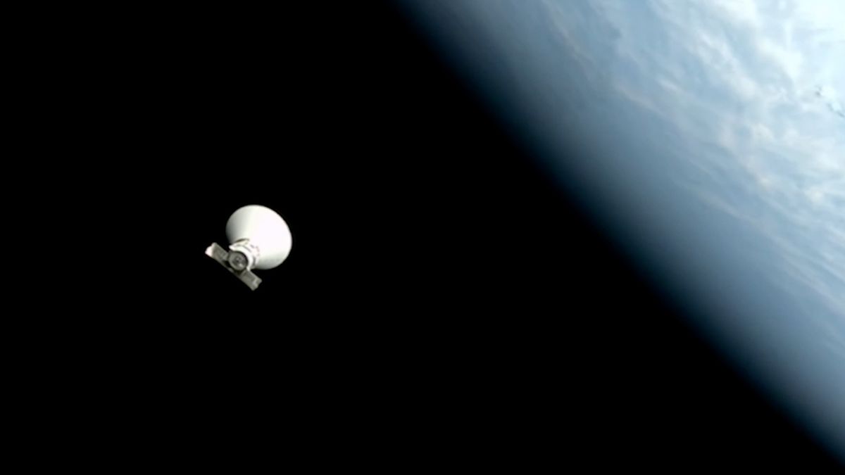 a white, conical spacecraft floats in the blackness above space. a blue and white earth can be seen along the rightmost edge of the photo