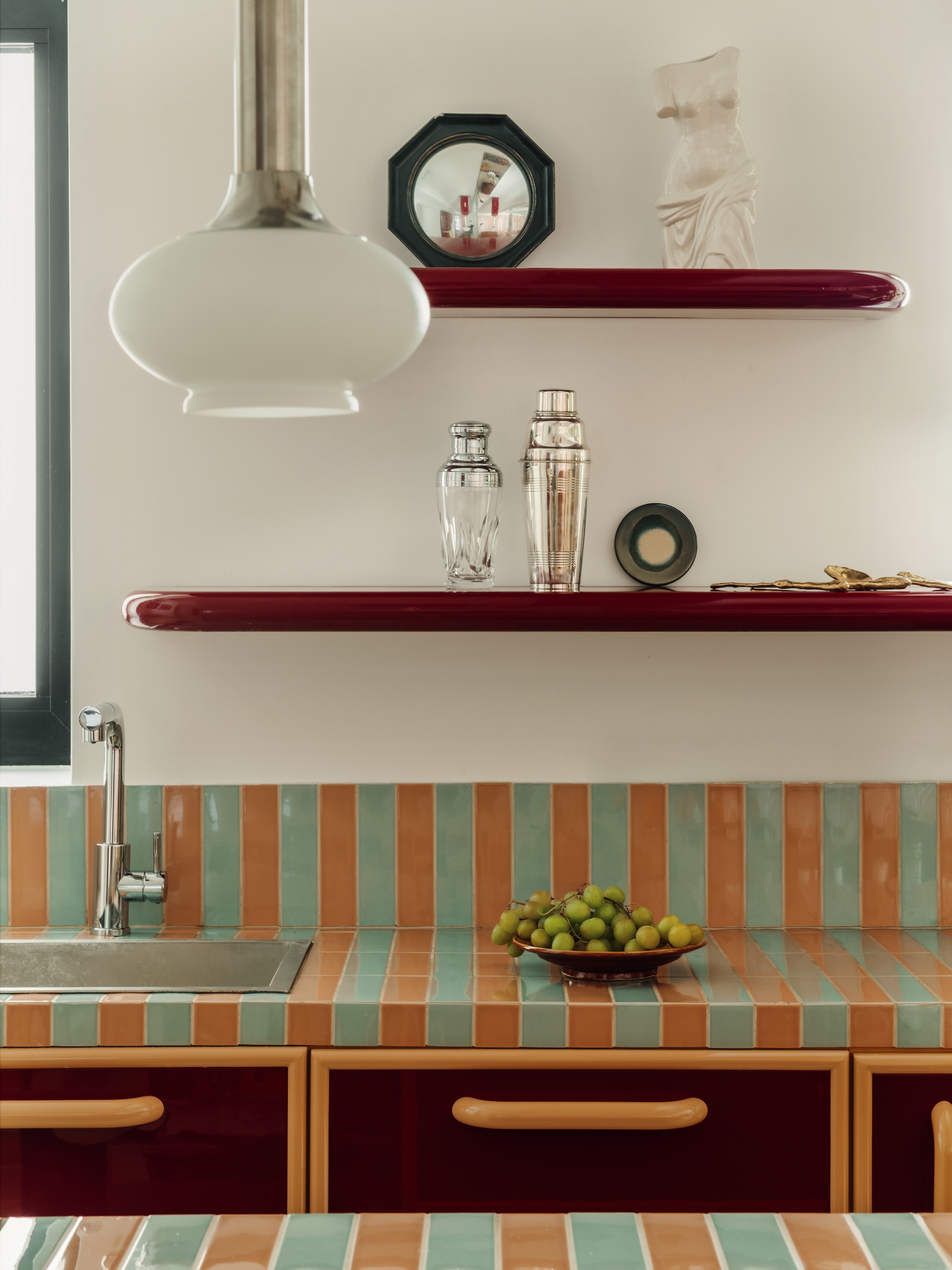 A kitchen counter with teal and sherbet orange tiles and lacquered accents