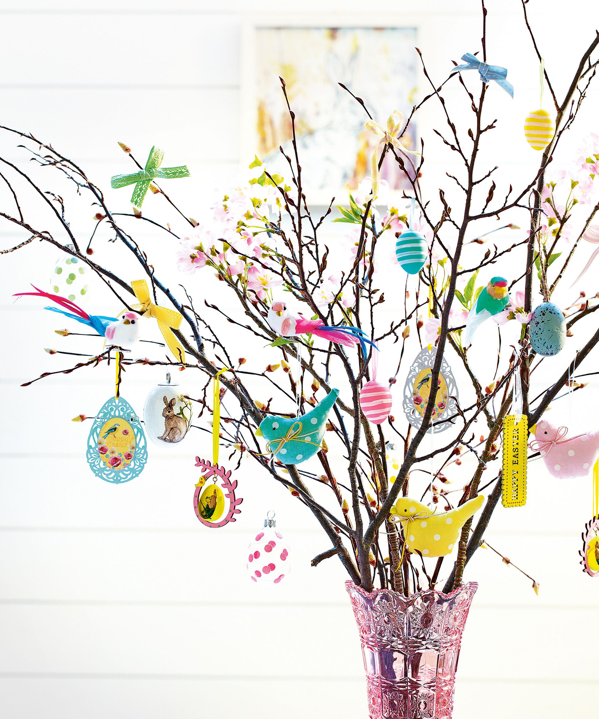 Blossom twig tree with hanging Easter decorations in pink vase