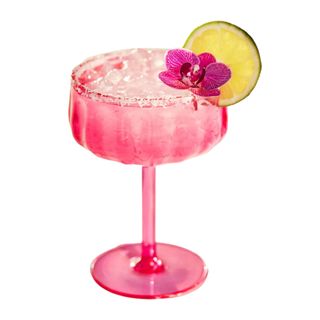Pink coupe glass with a cocktail and lime and a pink flower petal