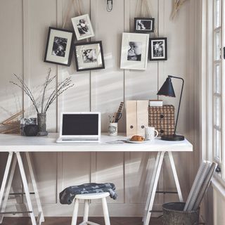 A home office with a desk and framed photographs on the wall