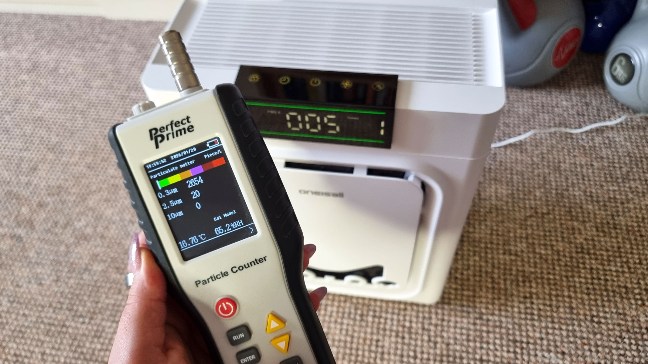 A picture of our reviewer testing the Oneisall Air Purifier using the Perfect Prime Air Particle monitor