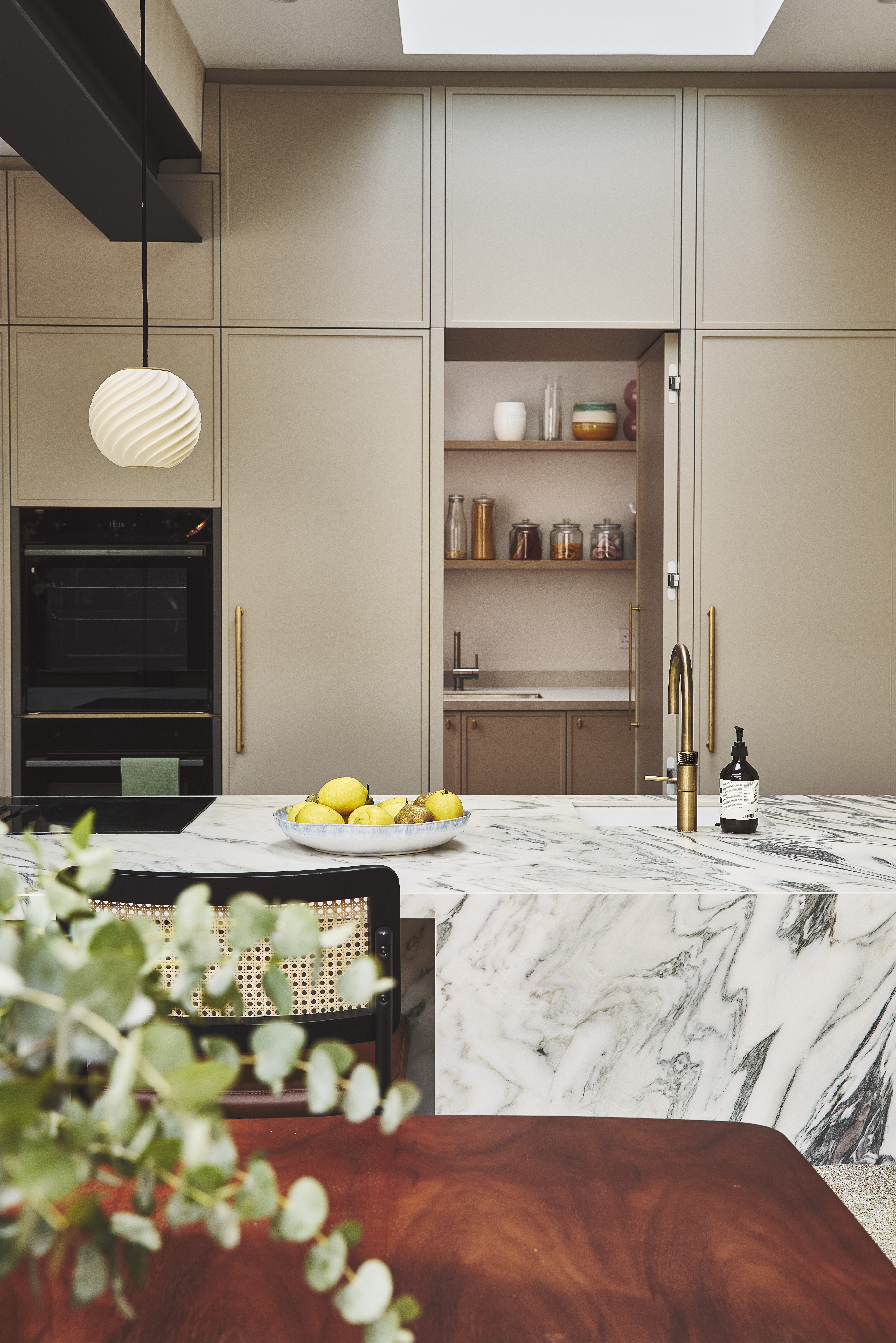 kitchen peninsula with cabinetry behind that leads on to a concealed pantry