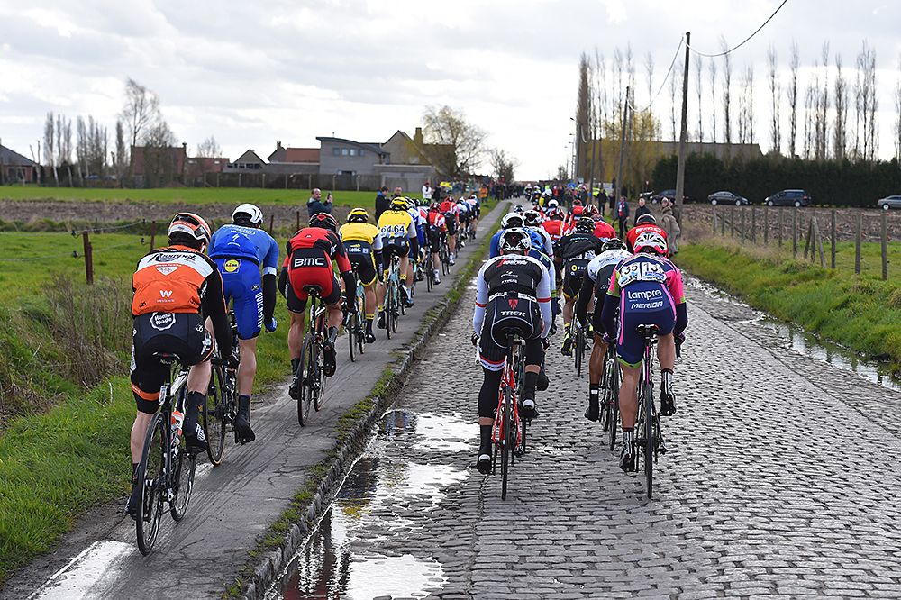 The peloton - half on cobbles, half on the sidewalk at Gent-Wevelgem