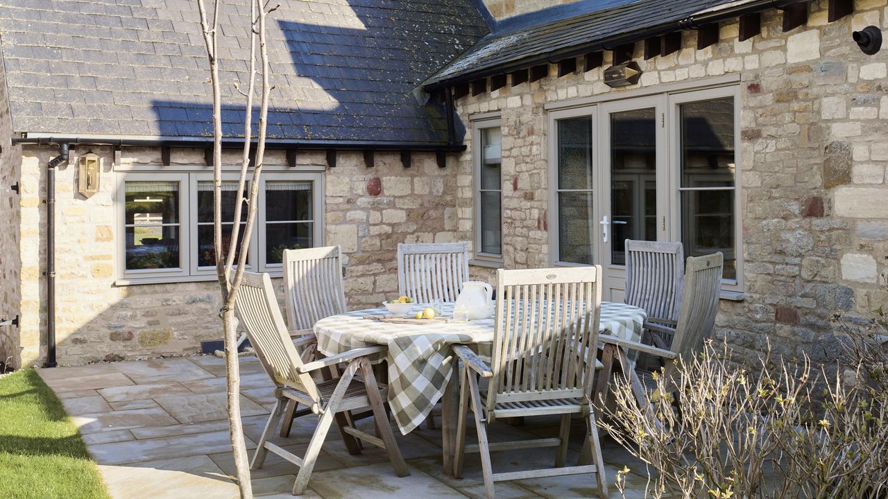 wooden table and chairs on a patio outside a cotswolds stone cottage in winter