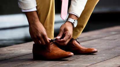 Male escort: A man tying his shoe laces