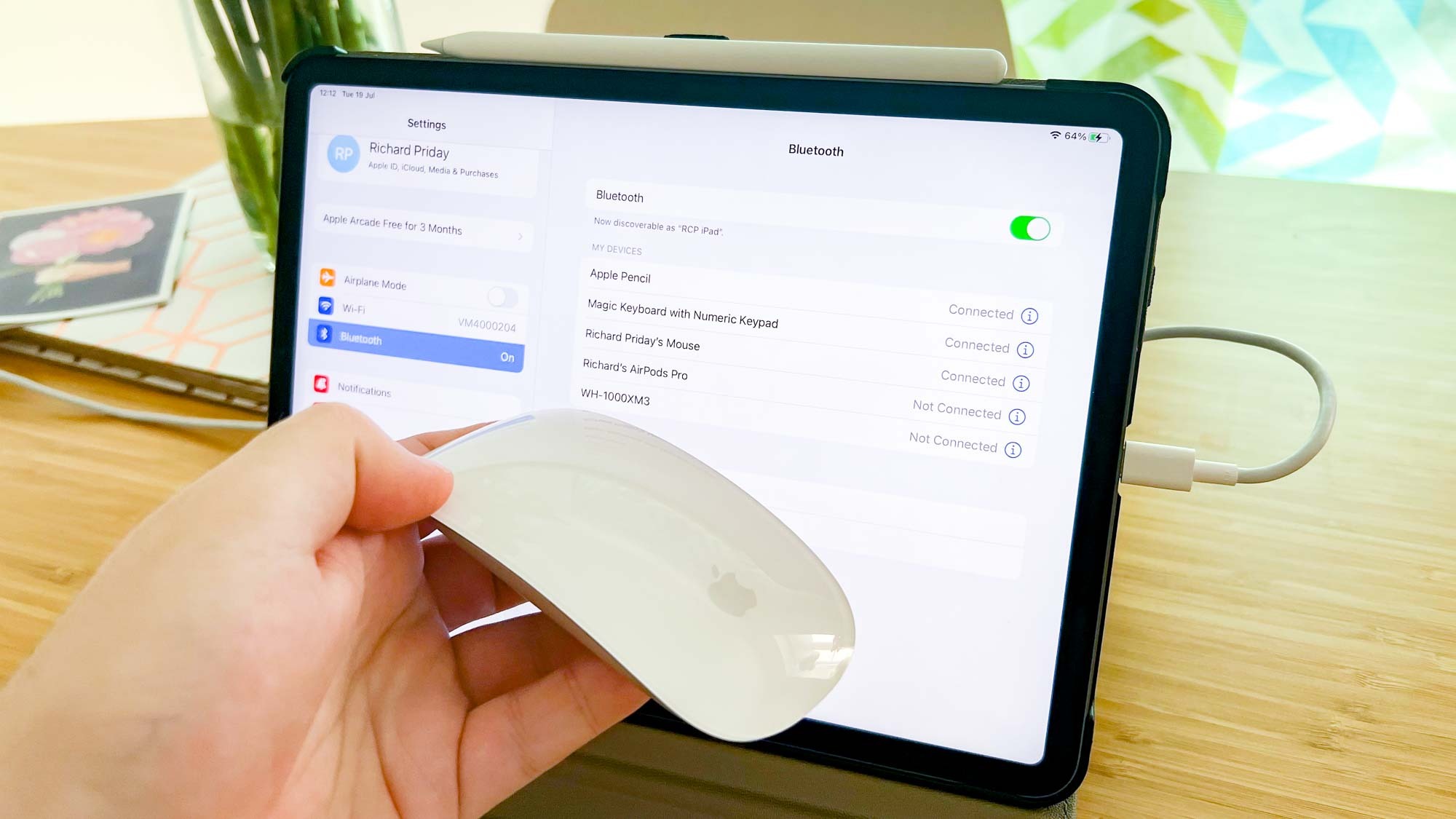 An iPad Pro with a Magic Mouse 2 held in front of it