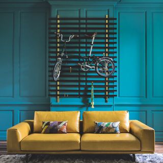 living room with bicycle hanging on teal wall and yellow sofa set