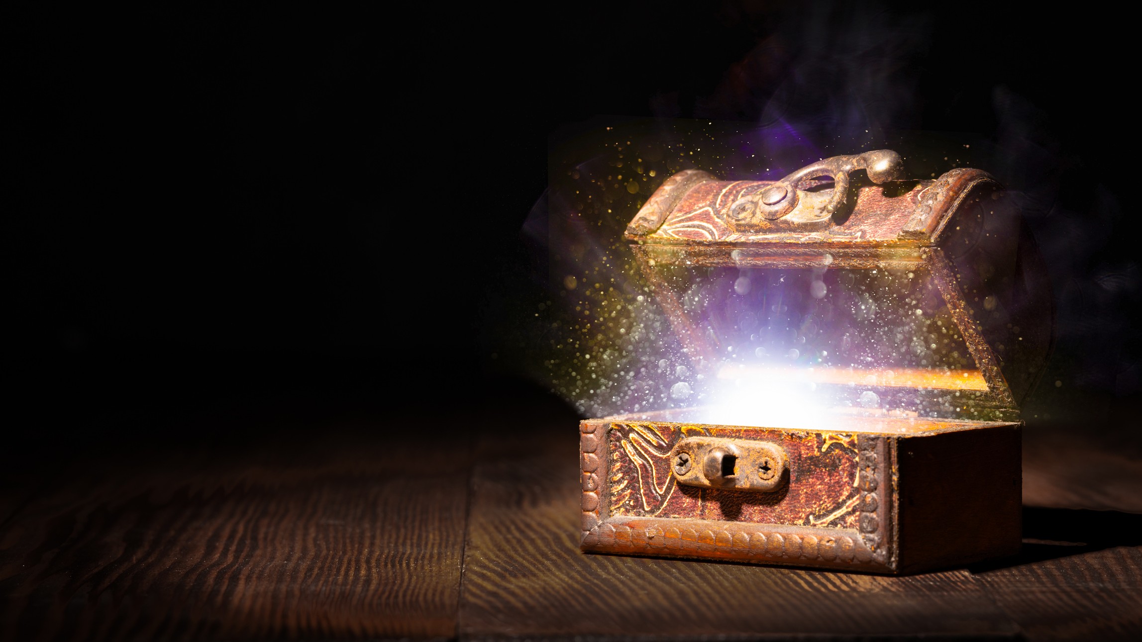 Treasure box half opened in a dimly lit room with magic lights coming out of the box