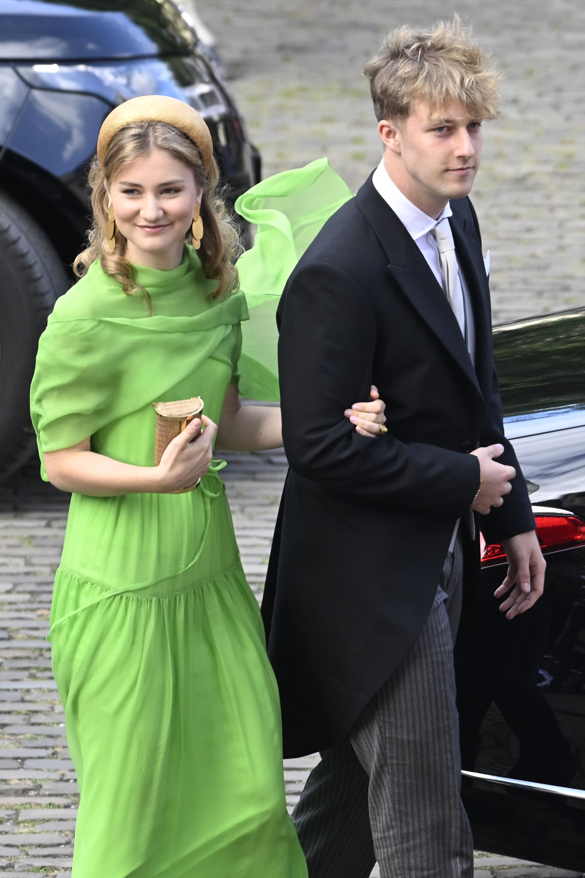 Princess Elisabeth wearing a neon green dress walking on the arm of her brother Prince Emmanuel