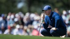 Rory McIlroy crouches on the green
