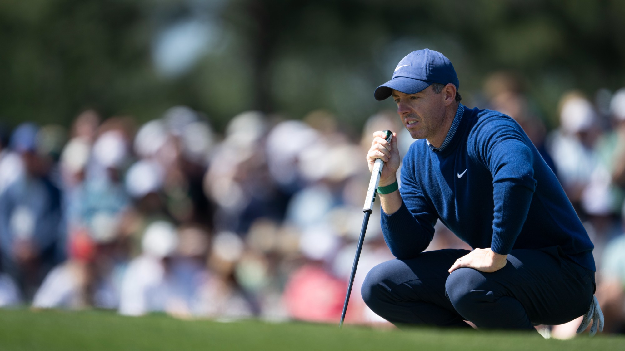 Rory McIlroy crouches on the green