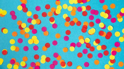 Paper confetti in bright colors on teal backdrop