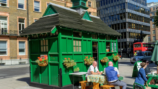 Customers sit outside a green-painted cabmen's shelter that has been converted into a cafe in London